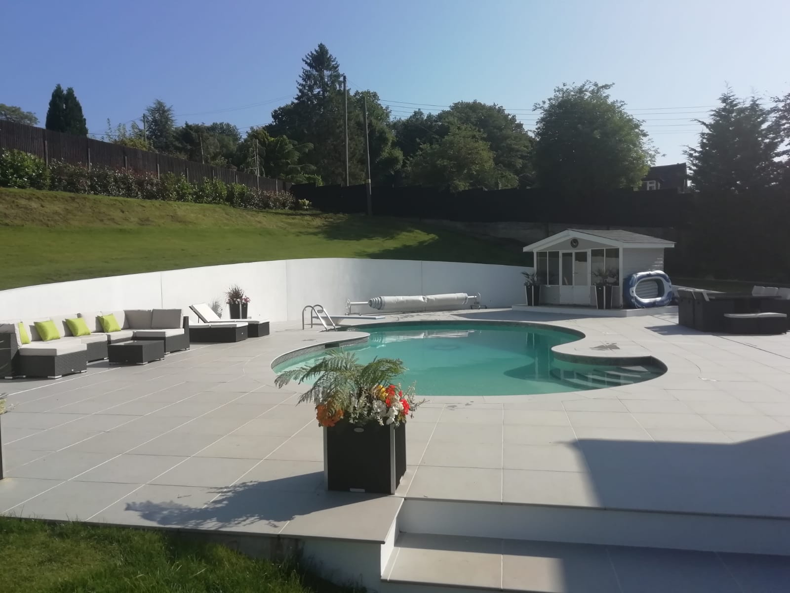 outdoor garden white patio with small circular swimming pool, garden house and deckchairs