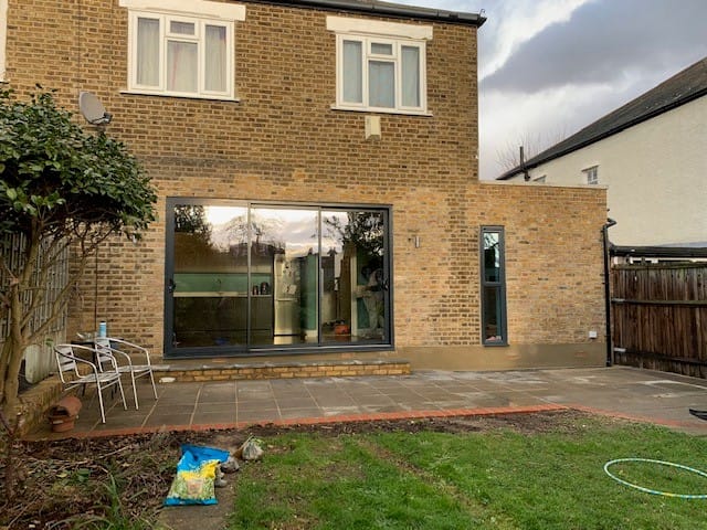 garden view of brick home with large glass doors